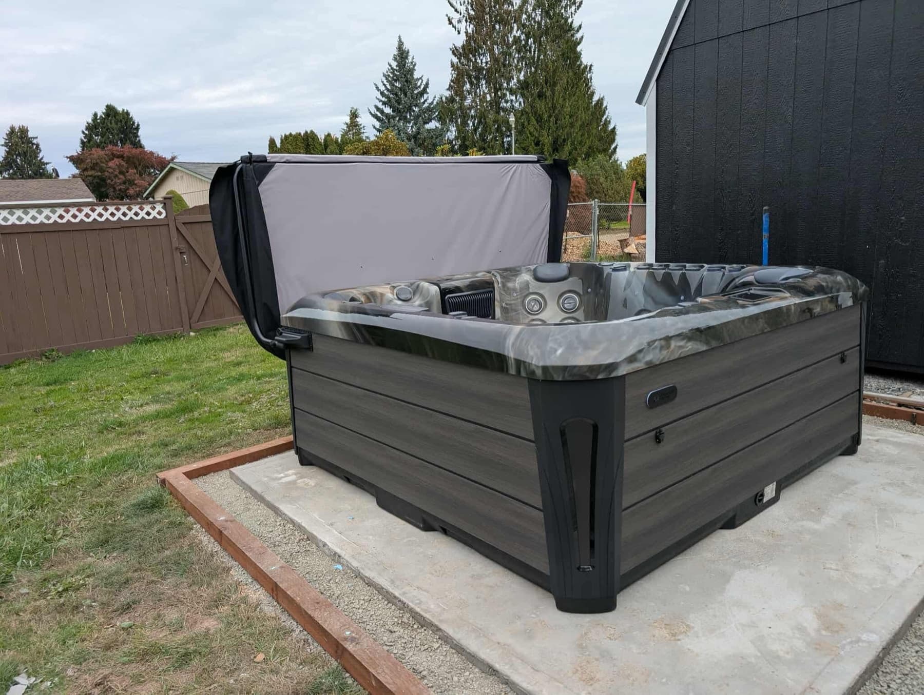 Hot tub with the cover open in a fenced backyard