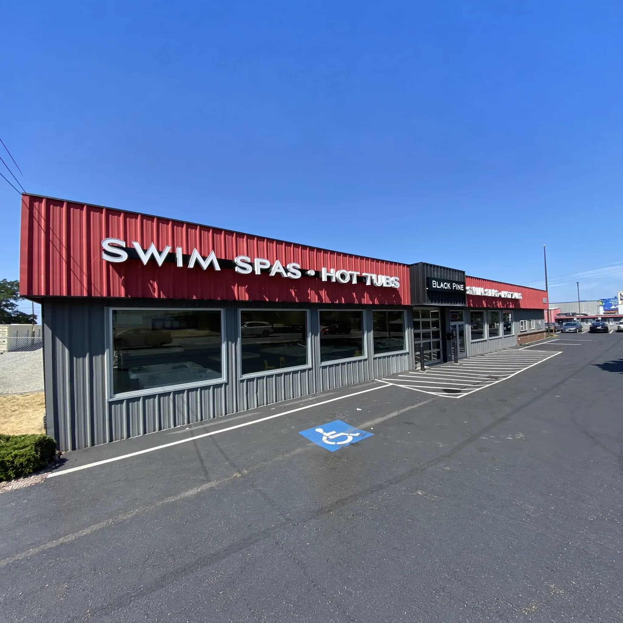Black Pine building in Tacoma with the Swim Spas and Hot Tubs sign across the red roofline and showroom windows below