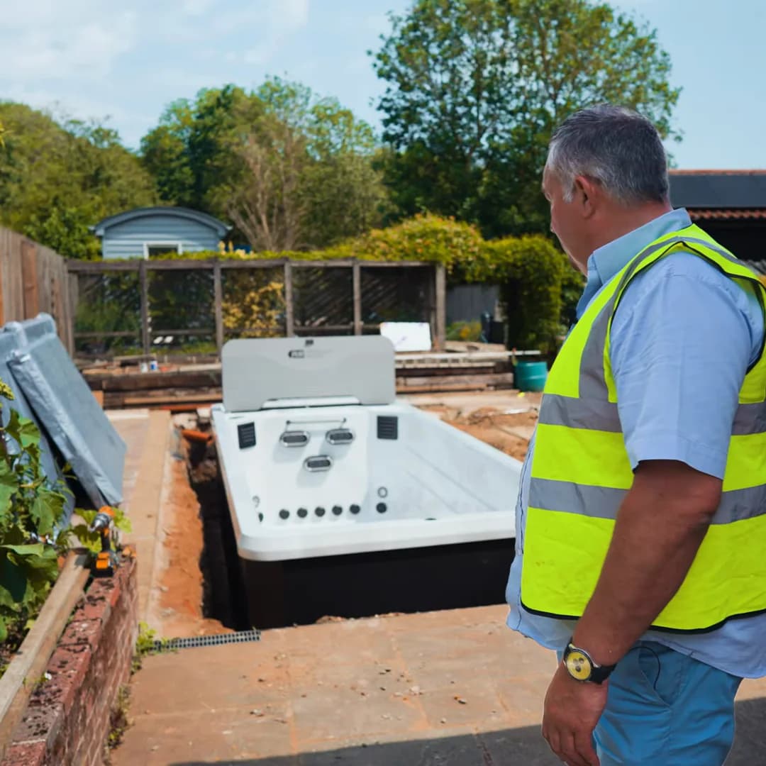 A Platinum Spas dealer standing beside a newly installed Atlas mini pool in a customer's garden
