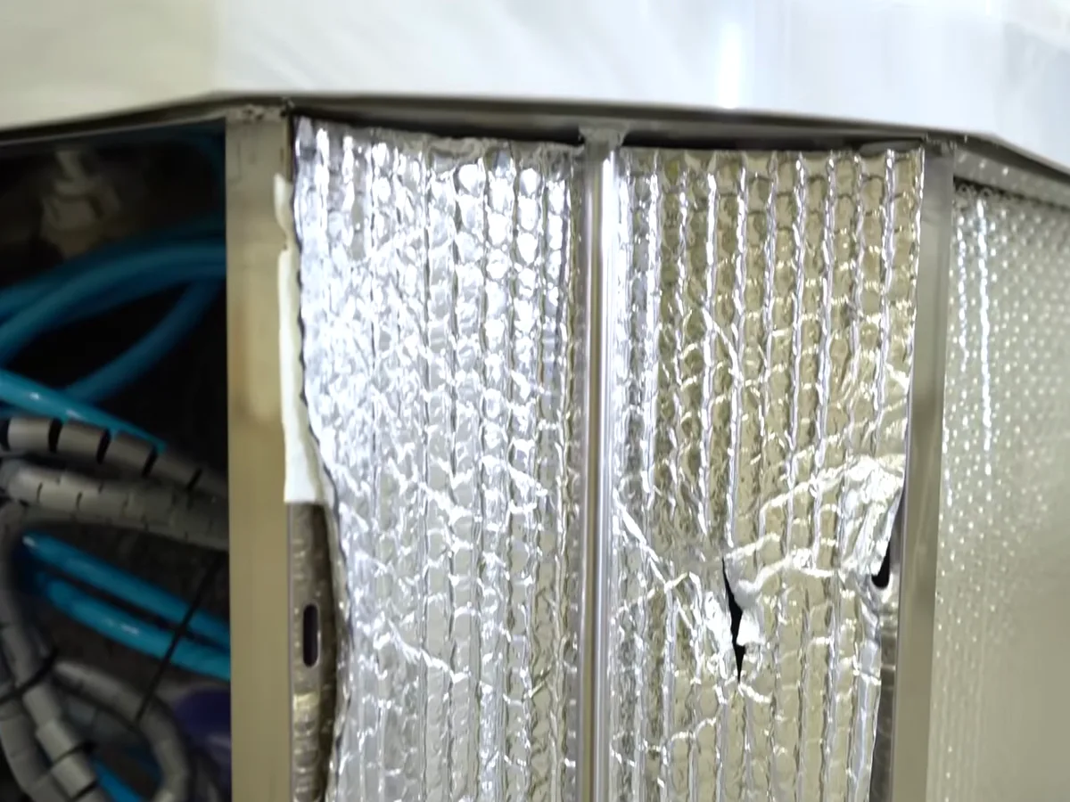 Foil insulation panels lining the inside of a Platinum Spas cabinet beside the plumbing